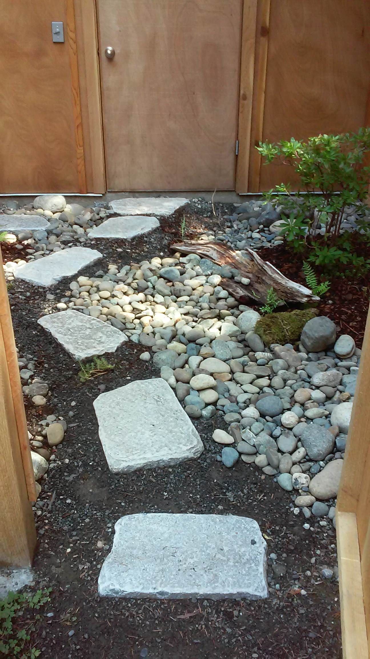 A stone walkway leading to a door in a garden.