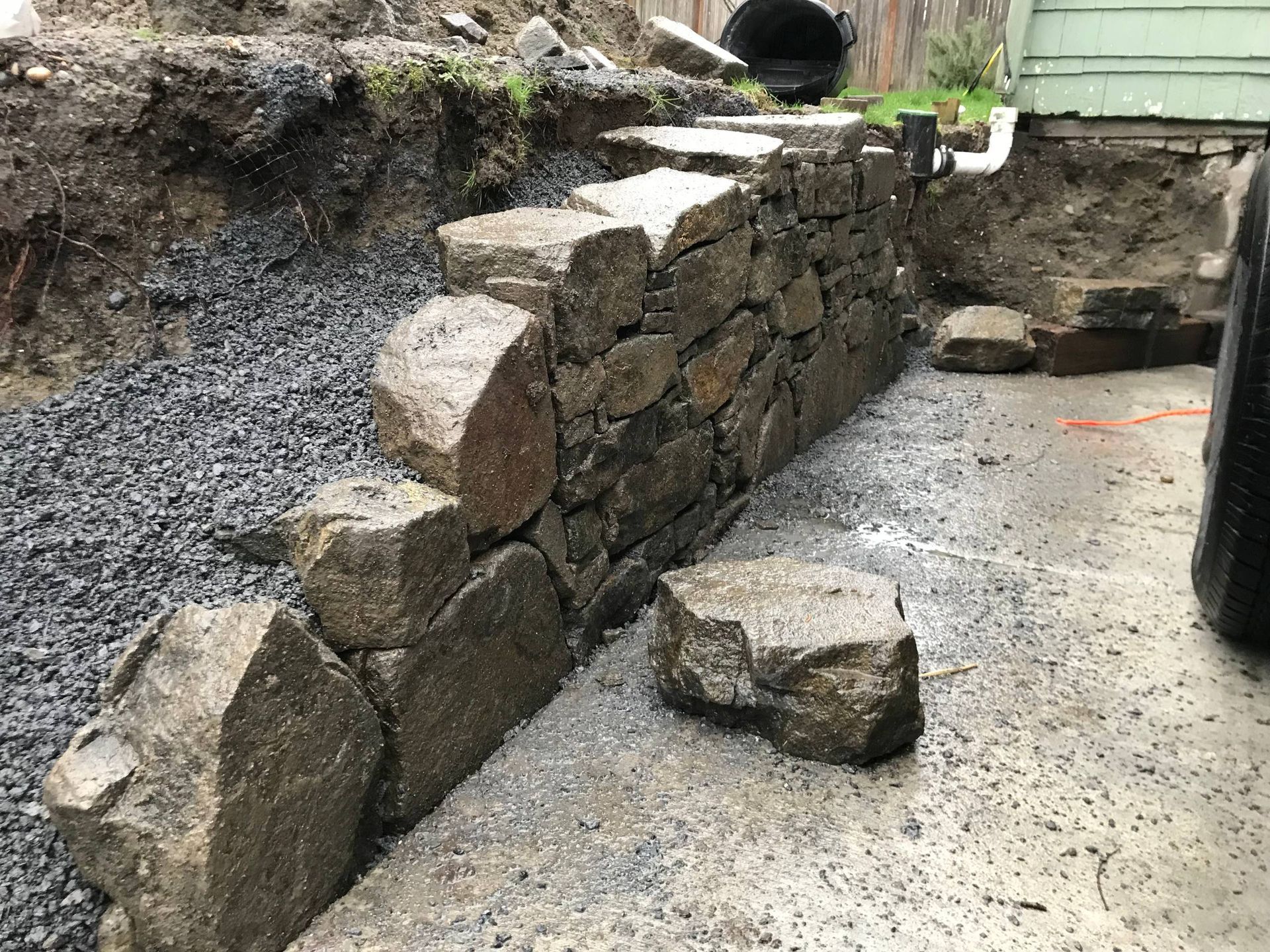 A stone wall is being built next to a pile of gravel.