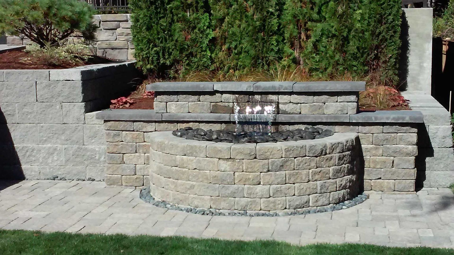 A fire pit is built into a brick wall in a backyard