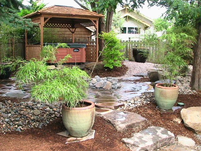 A garden with a gazebo and a hot tub