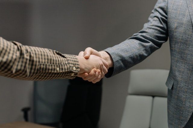 people-shaking-hands-one-person-is-wearing-a-brown-checkered-shirt-and-the-other-wearing-a-suit