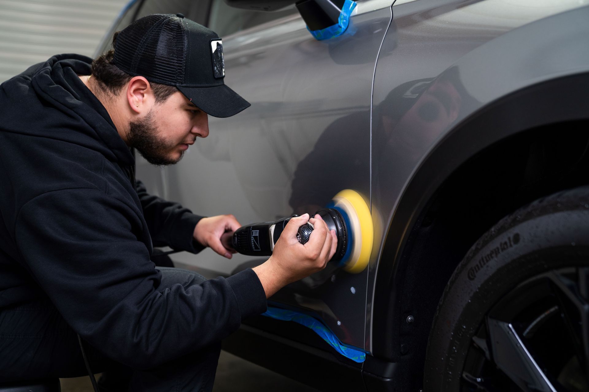 A man is paint polishing a 2024 Honda CRV car with a polisher .
