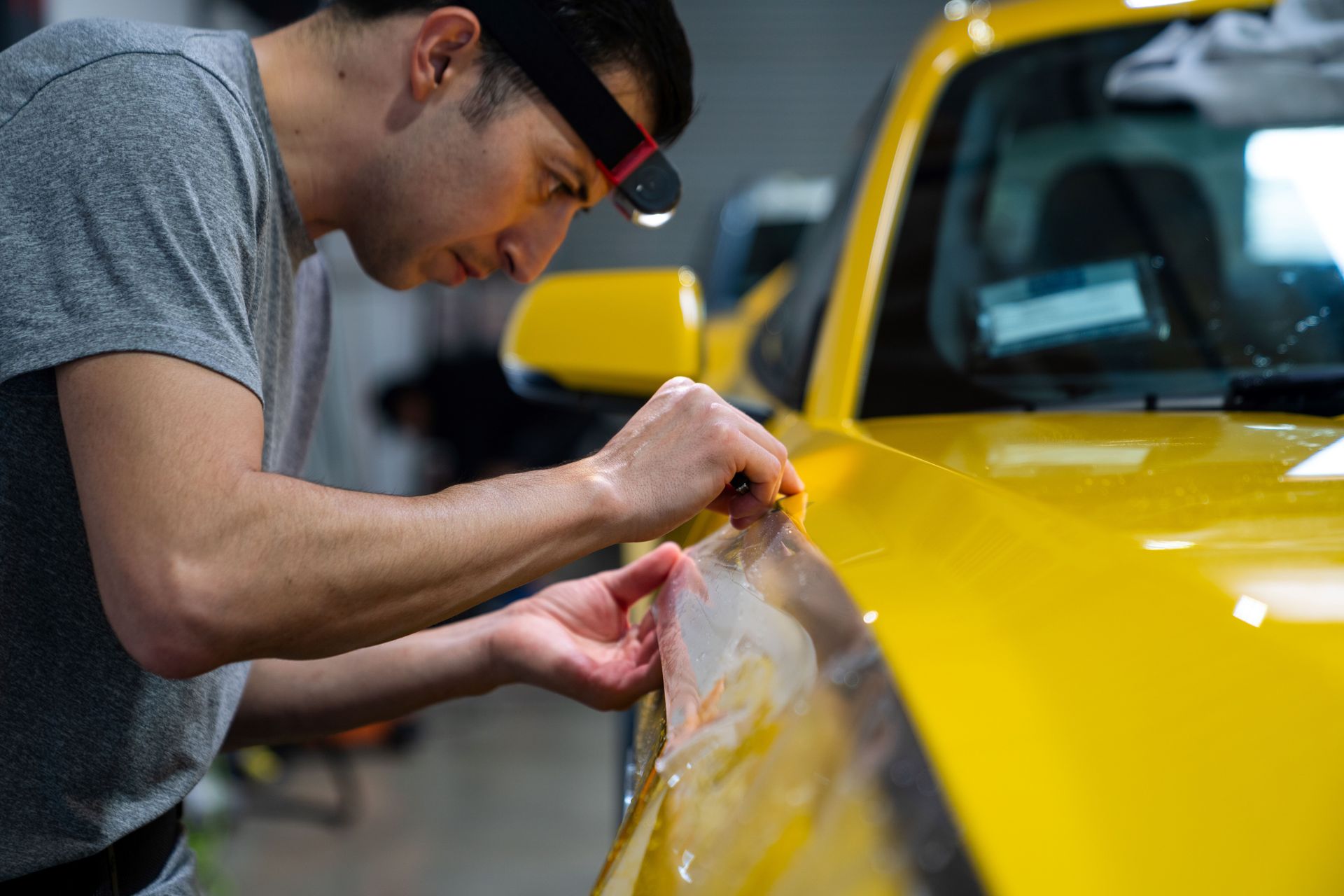 A man is Trimming a 2024 Mustang GT Hood with PPF .