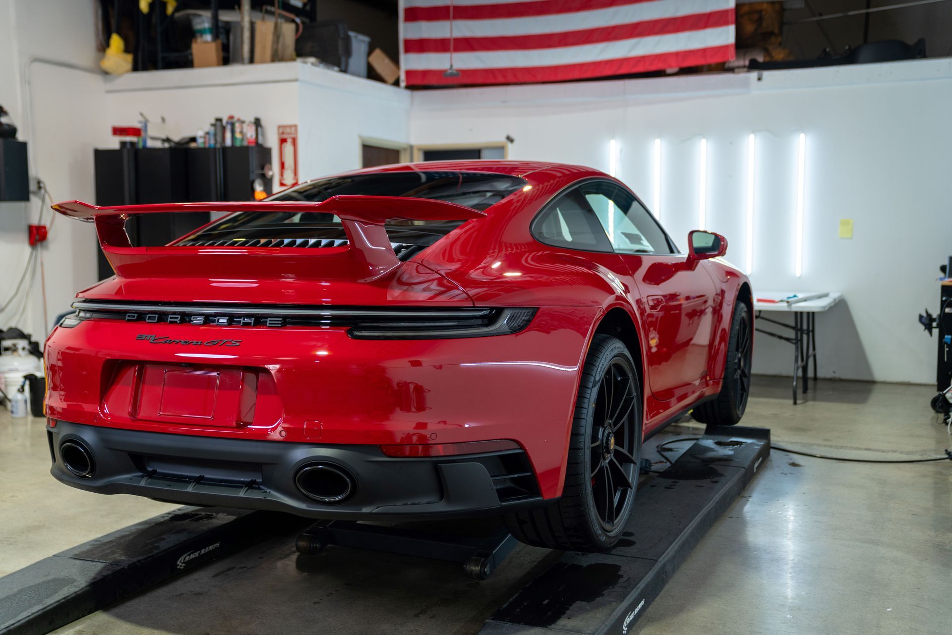 A red porsche 911 is parked on a lift in a garage .