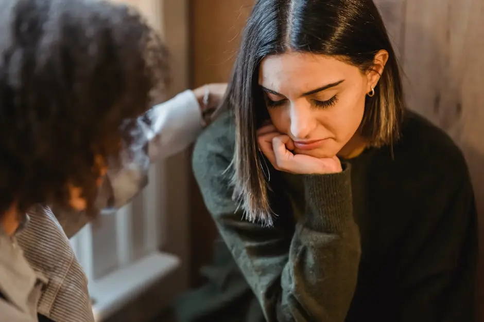 A man is comforting a woman who is sitting down with her head resting on her hand.