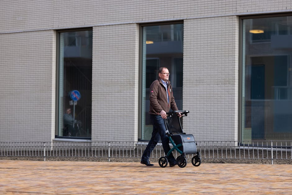 A man is walking with a walker in front of a building.