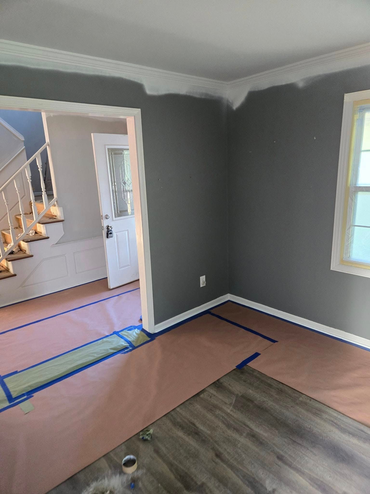 A room with a staircase and a window is being painted.