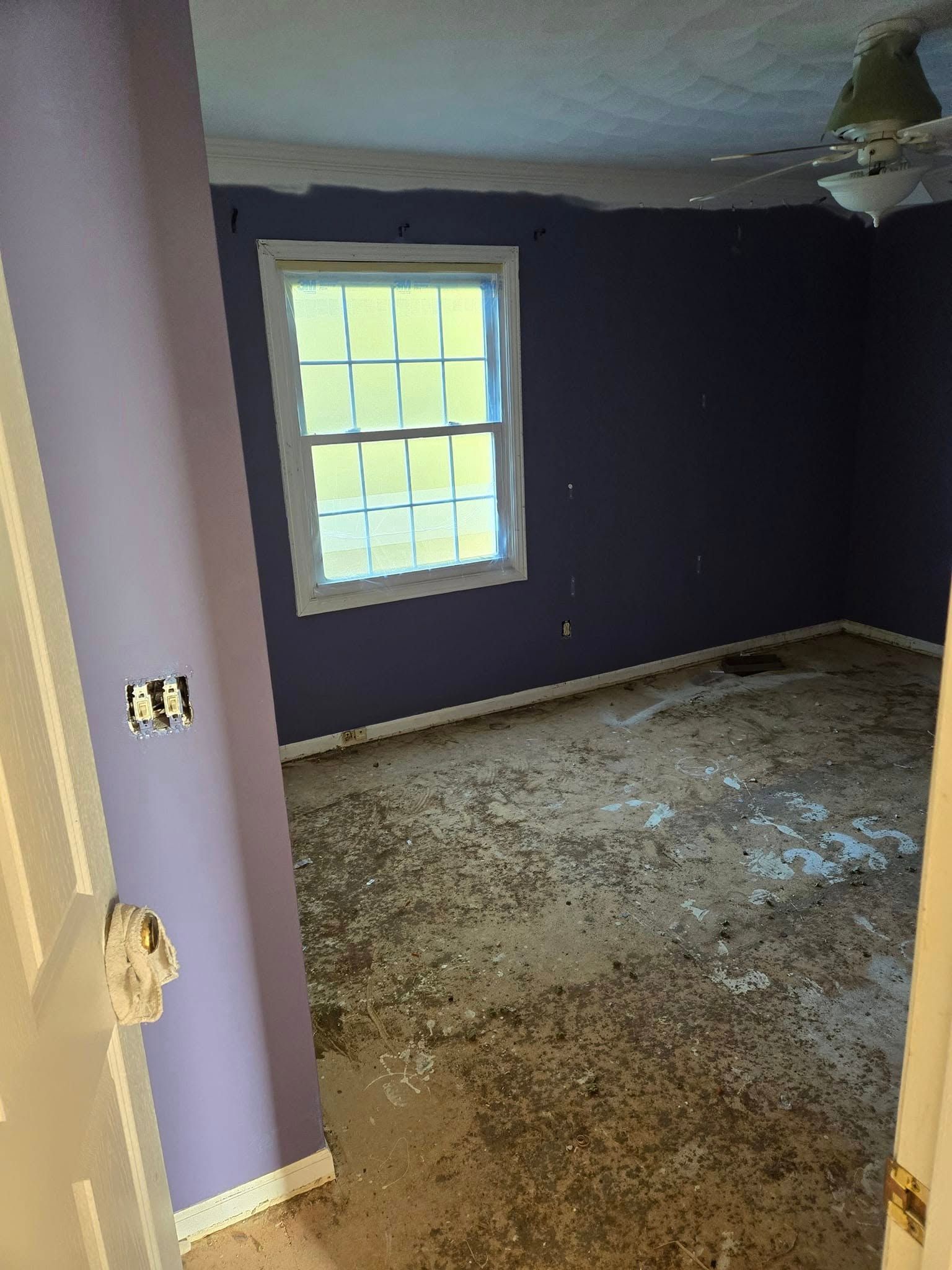 An empty room with purple walls and a window.