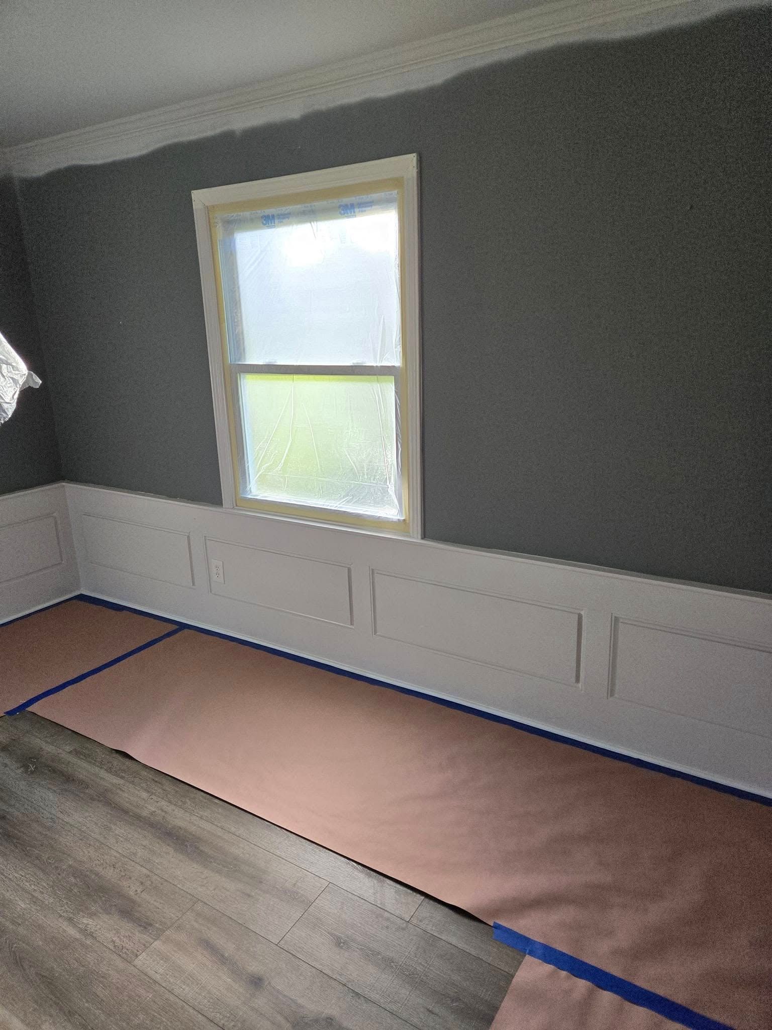 A room with a window and a rug on the floor.