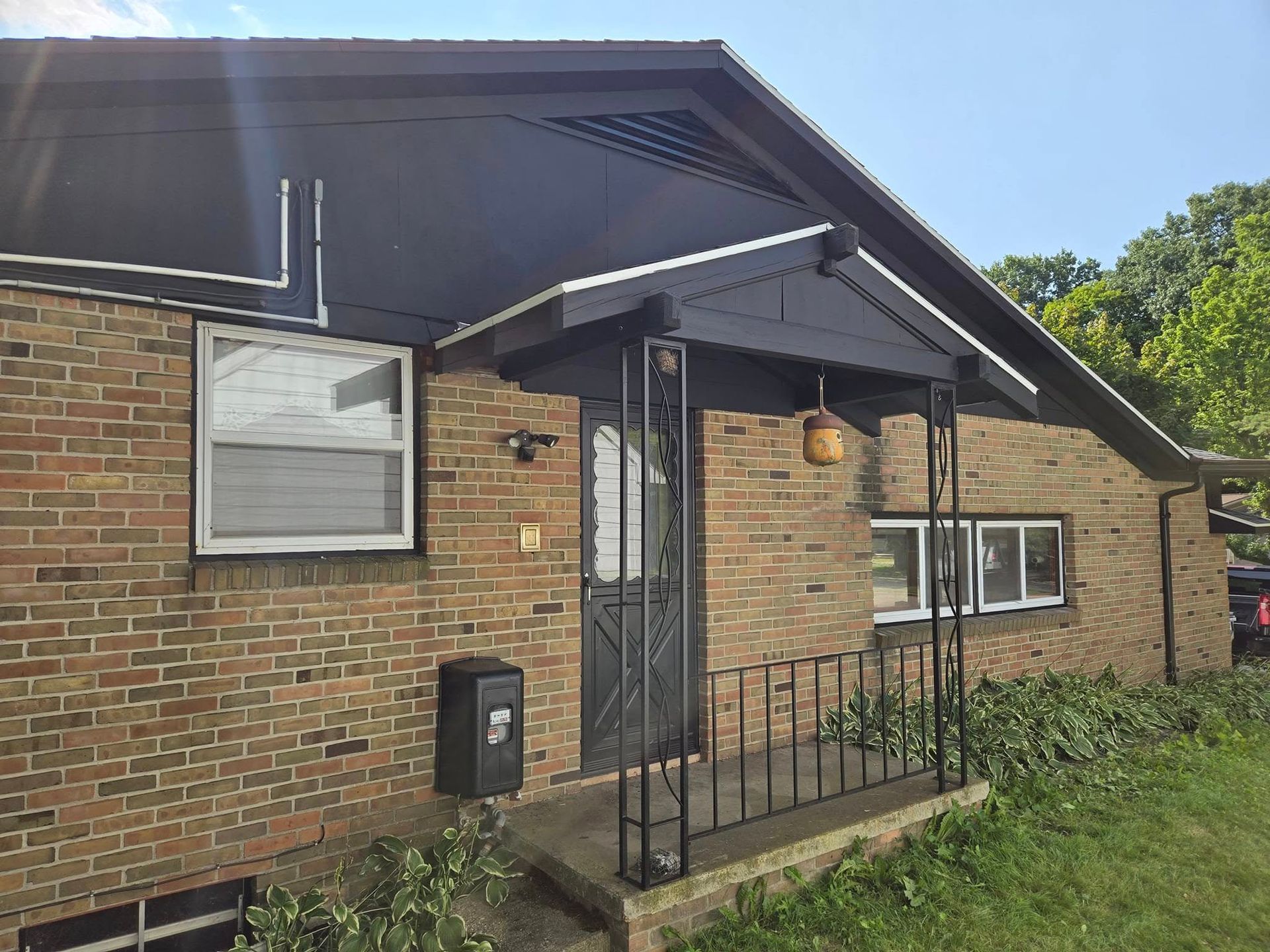A brick house with a black roof and a porch.