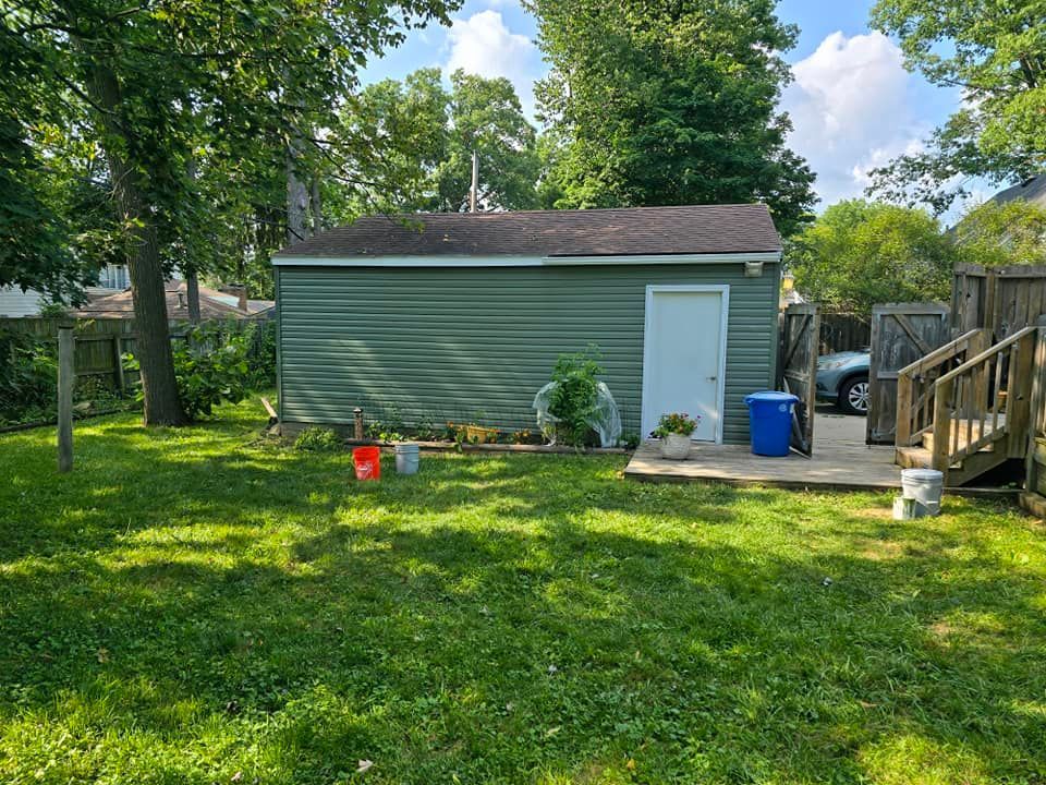 There is a shed in the backyard with a deck and stairs.