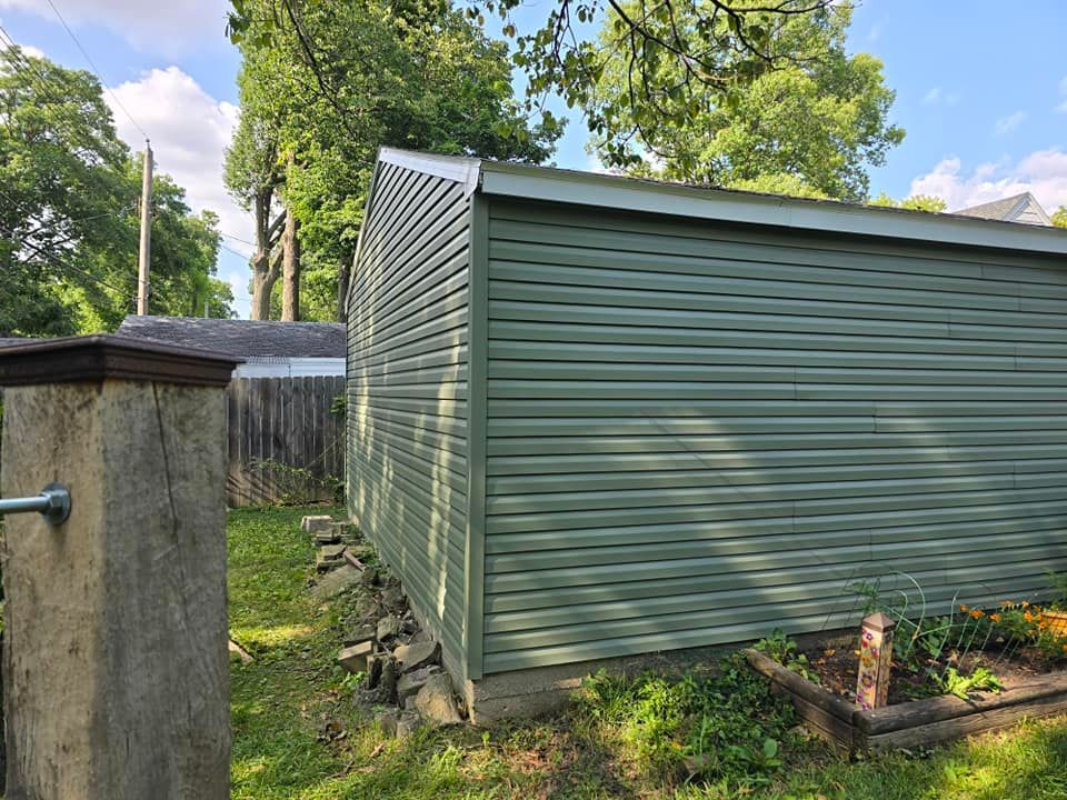 A green shed is in the backyard of a house.