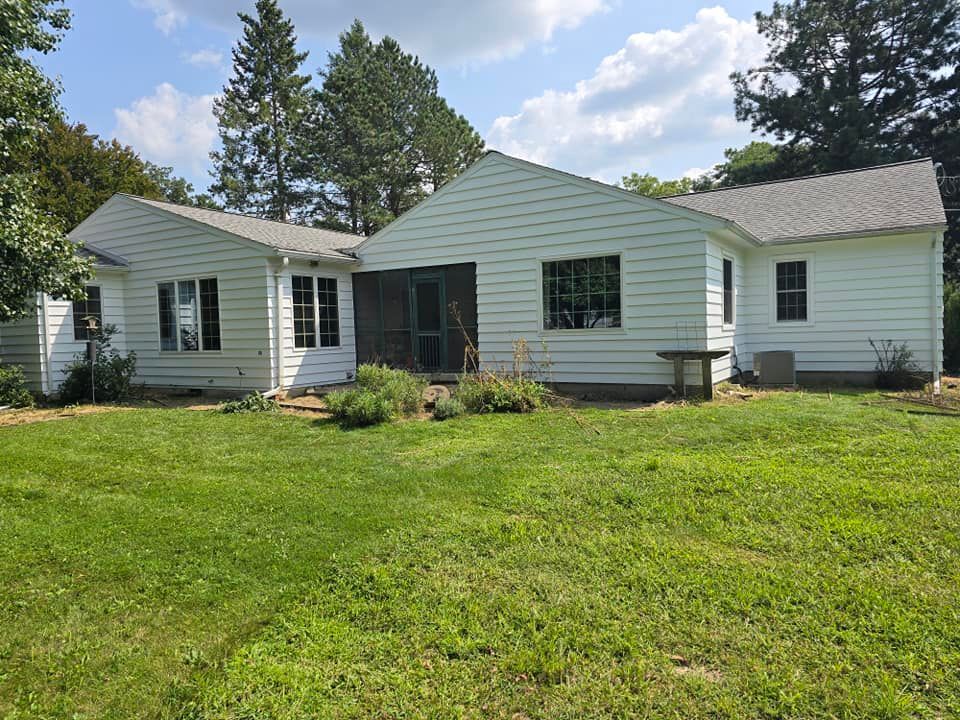 A white house is sitting on top of a lush green field.
