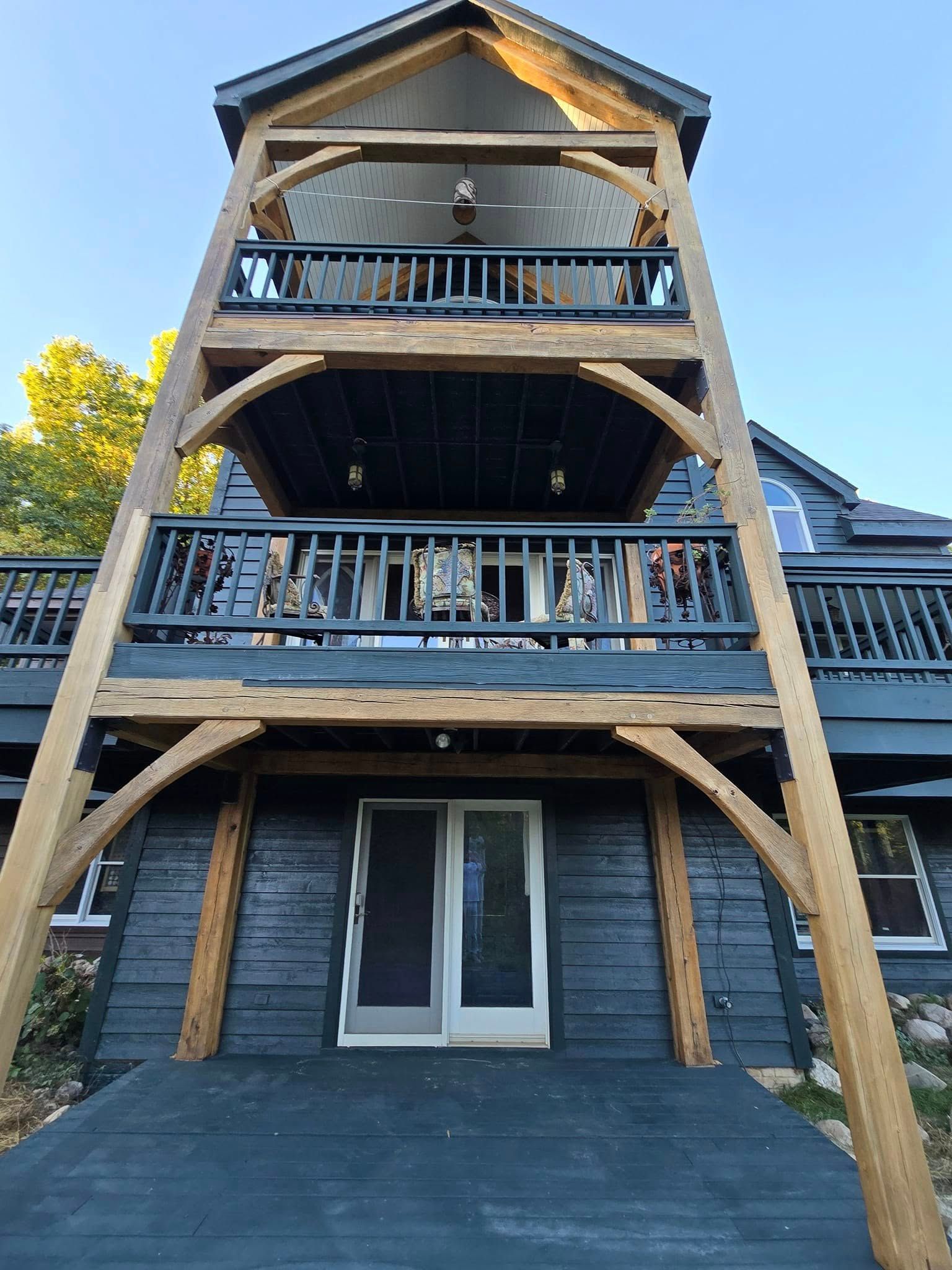 A large black house with a wooden deck and balconies.
