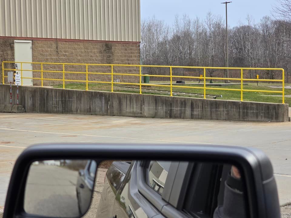 A truck is parked in front of a building with a yellow railing.