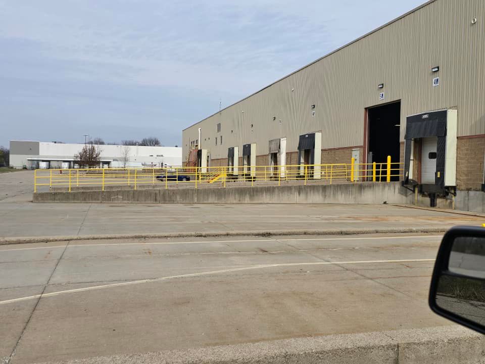 A warehouse with a lot of loading docks and a car parked in front of it.