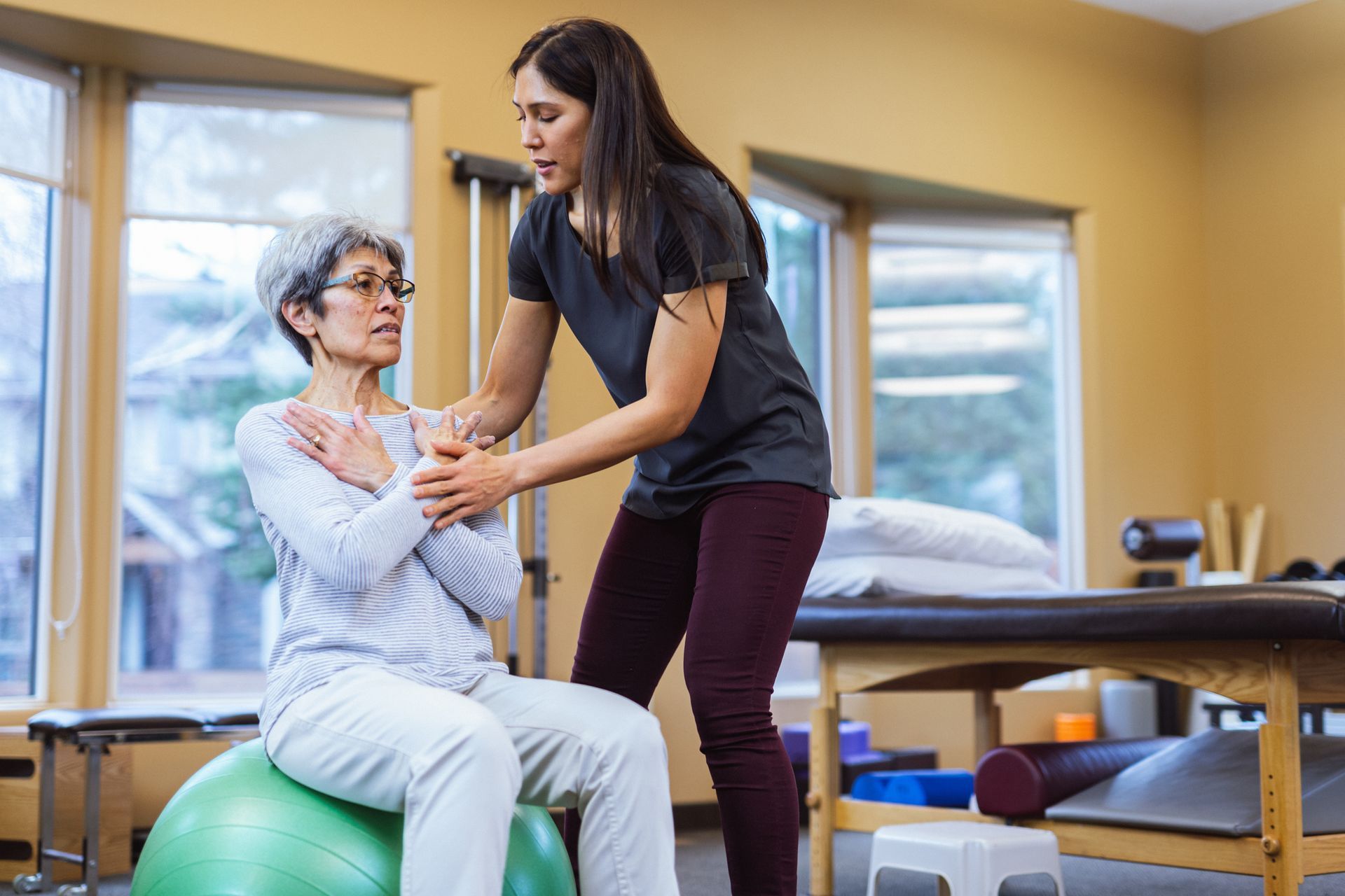 A woman is helping an older woman sit on an exercise ball – Minden, NE - Bethany Home