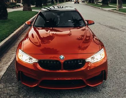 A red bmw m4 is parked on the side of the road.