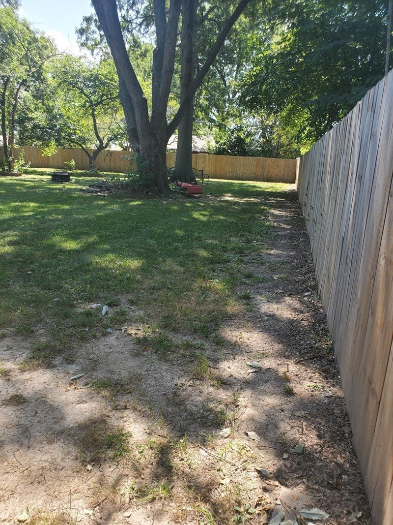 A wooden fence surrounds a lush green yard.