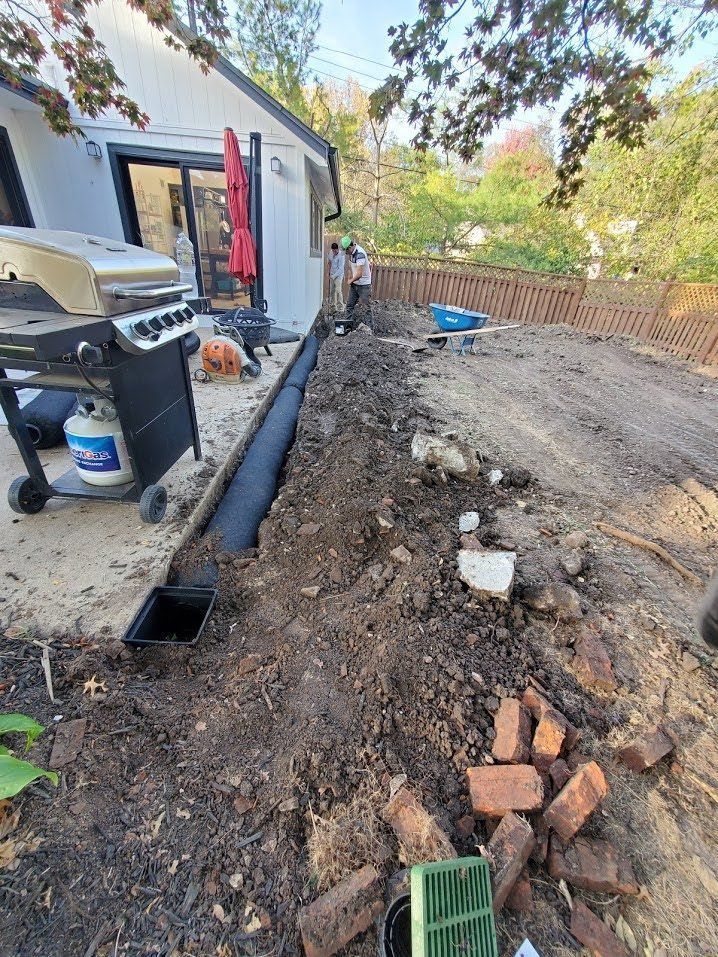 A grill is sitting on the side of a house next to a pile of dirt.