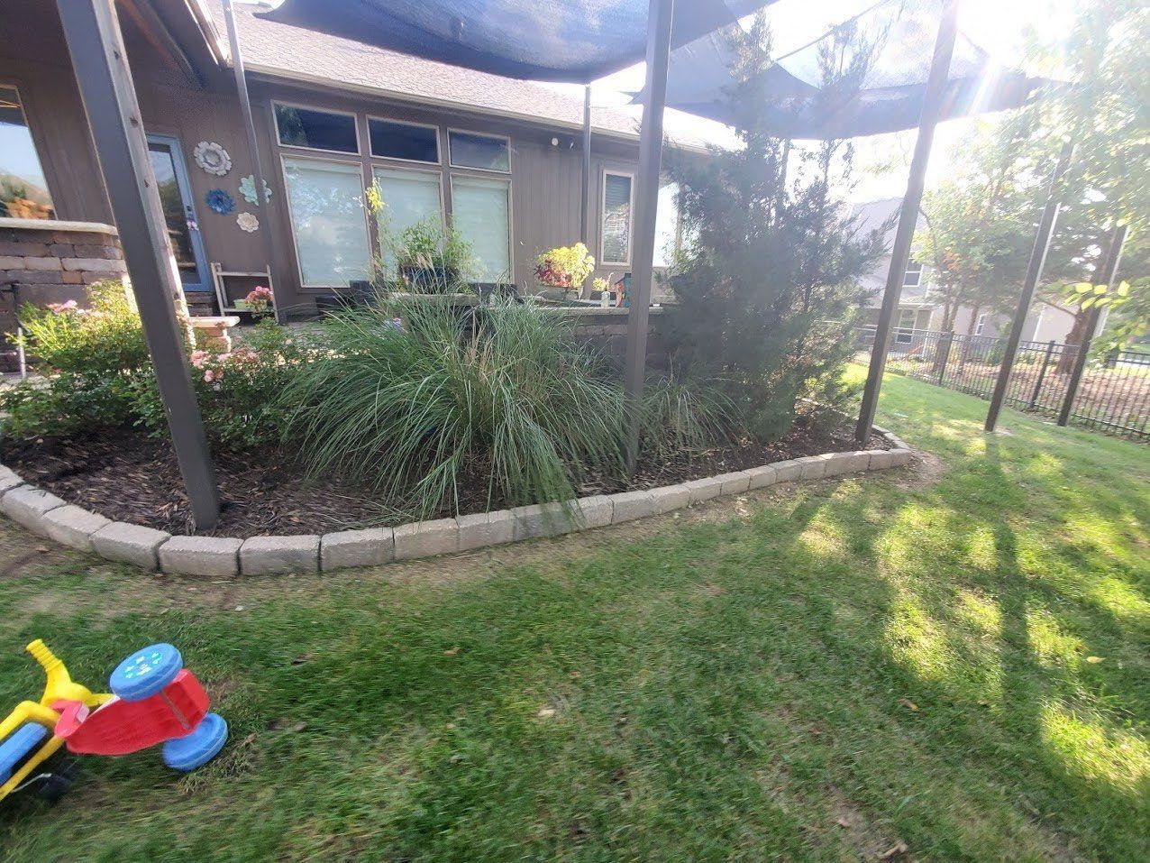 A toy plane is sitting in the grass in front of a house.