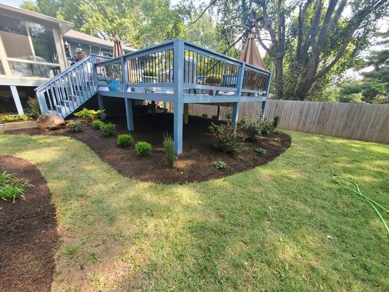 A blue deck with stairs leading up to it is in the backyard of a house.