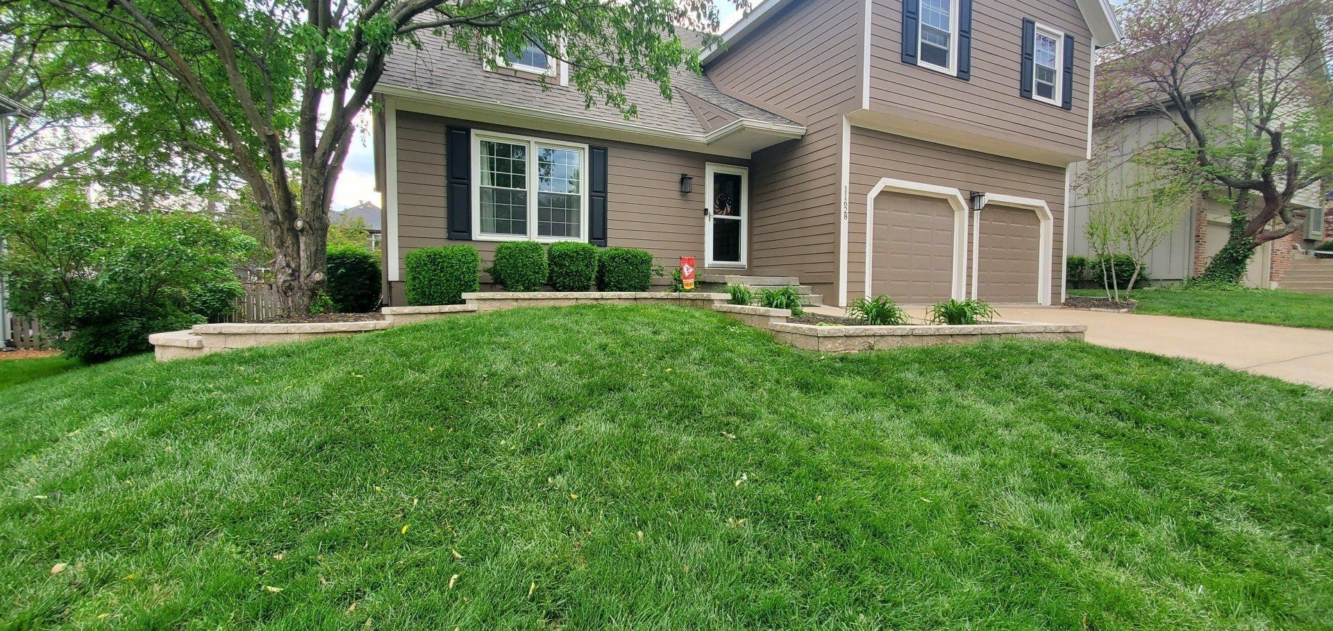 A brick house with a lush green lawn in front of it.