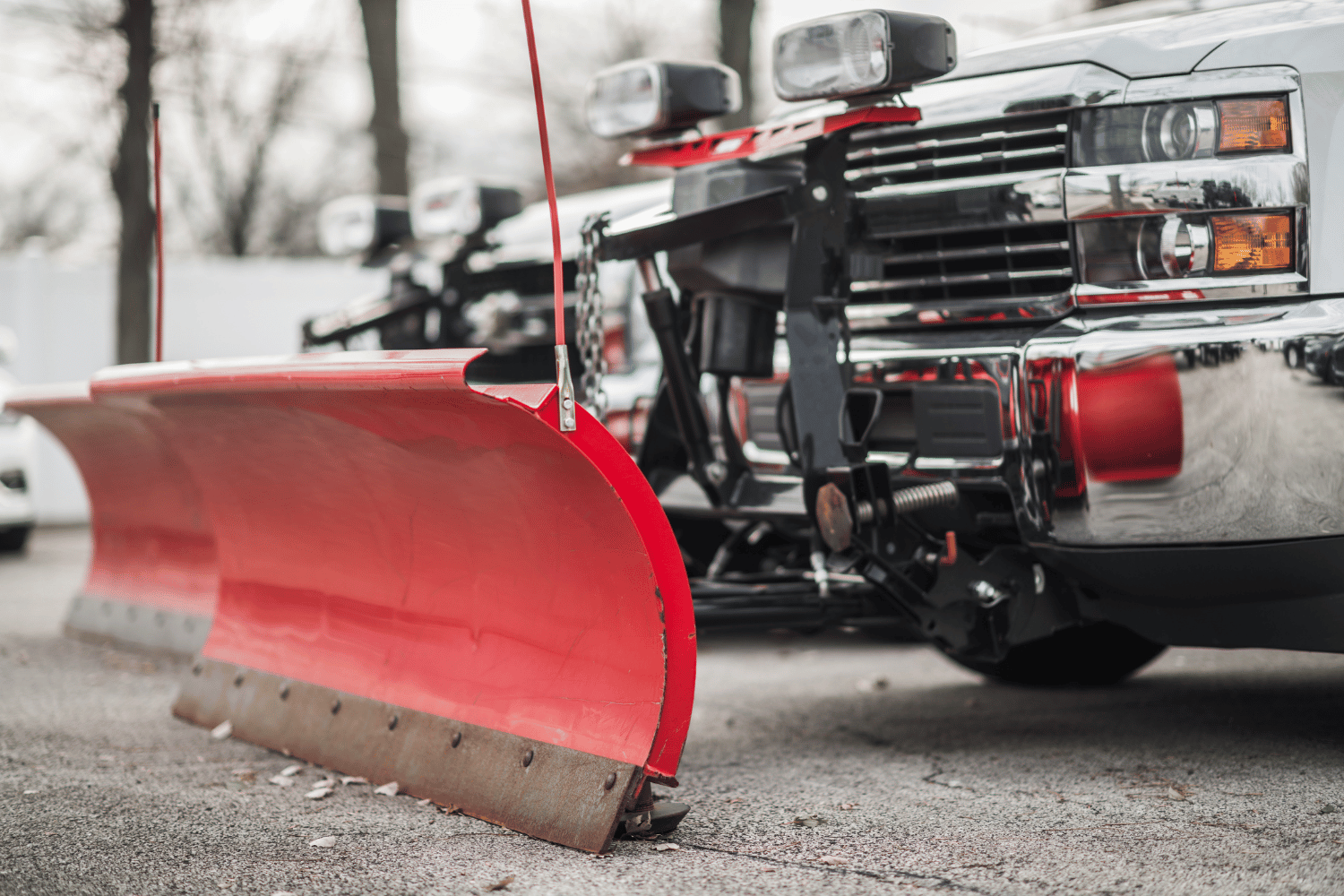 A snow plow is parked on the side of a truck.