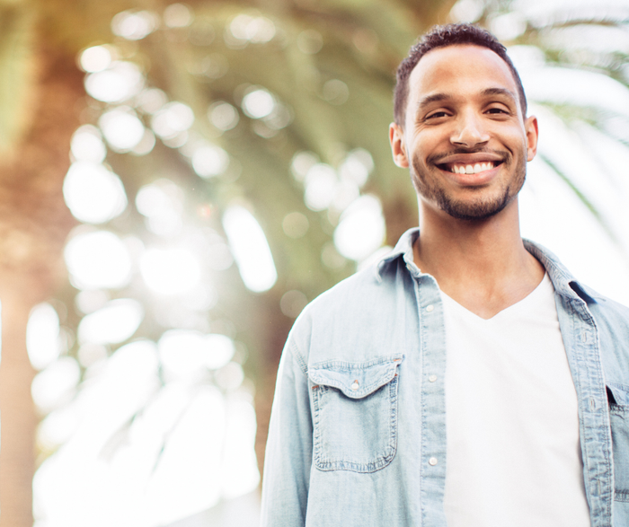 A picture of a man smiling in front of a tree.