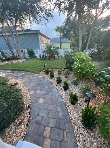 A brick walkway leading to a house in the backyard.