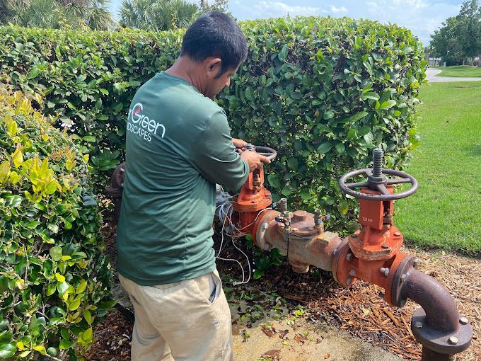 A man in a green shirt is working on a water pipe.