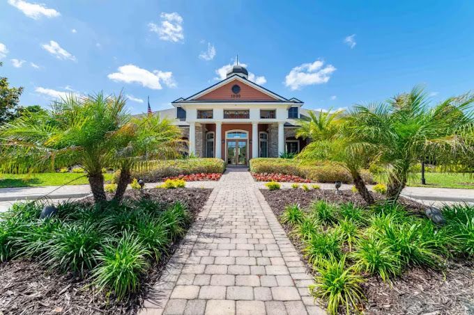 A brick walkway leading to a large building with palm trees in front of it.