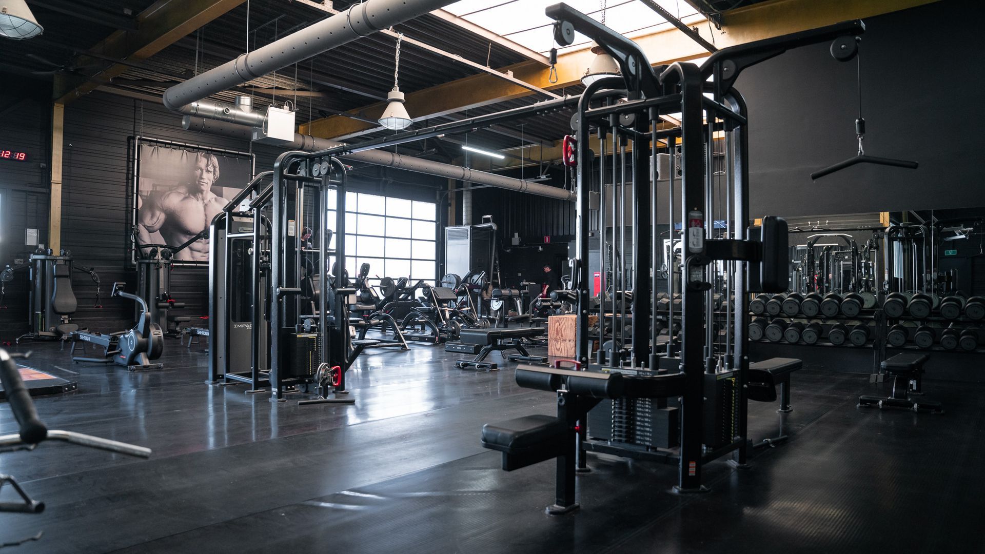 Een grote lege sportschool met veel fitnessapparatuur.
