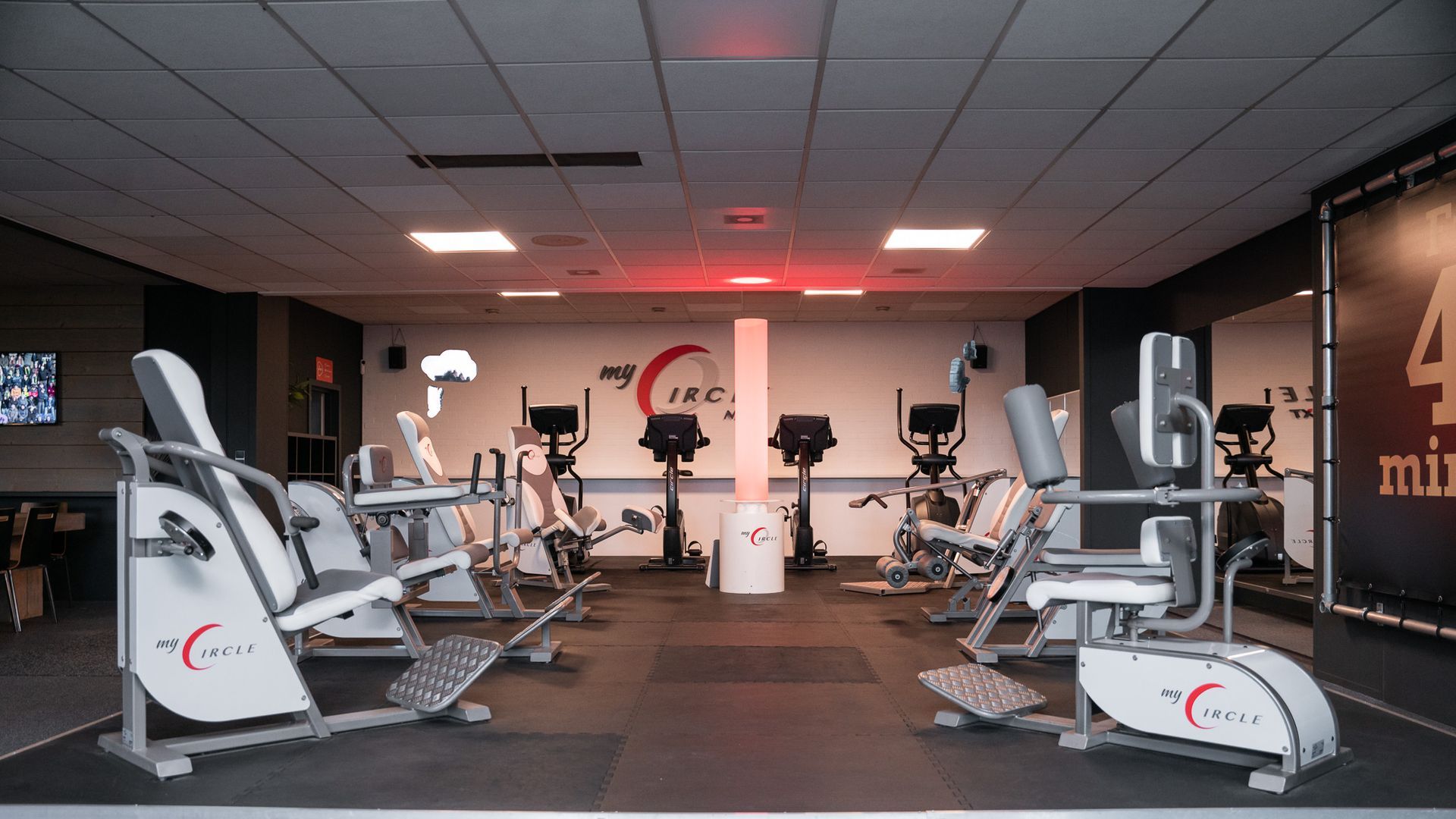 Een sportschool met veel fitnessapparatuur en een bordje waarop staat 4 min.