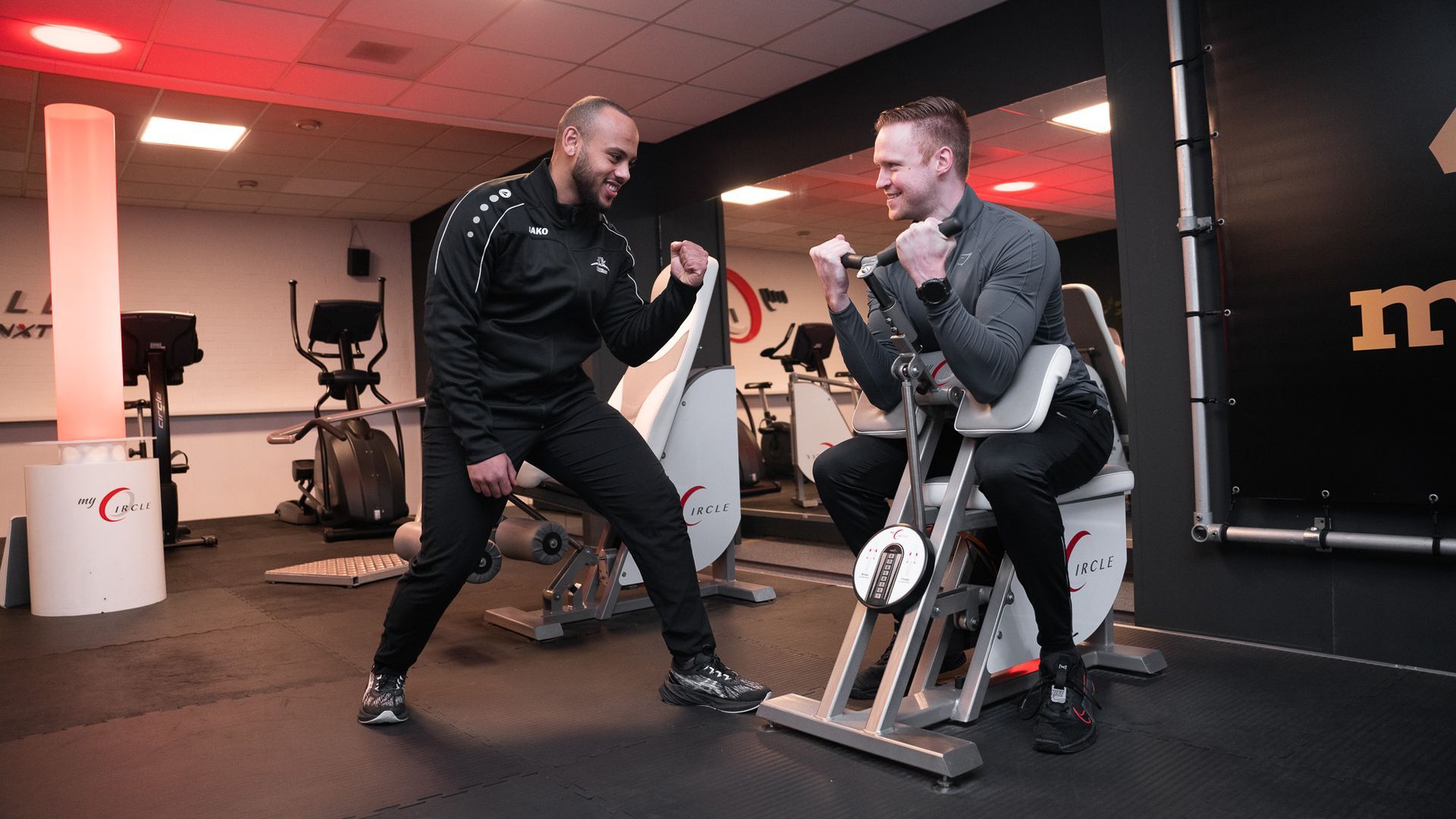 Twee mannen zitten op hometrainers in een sportschool.