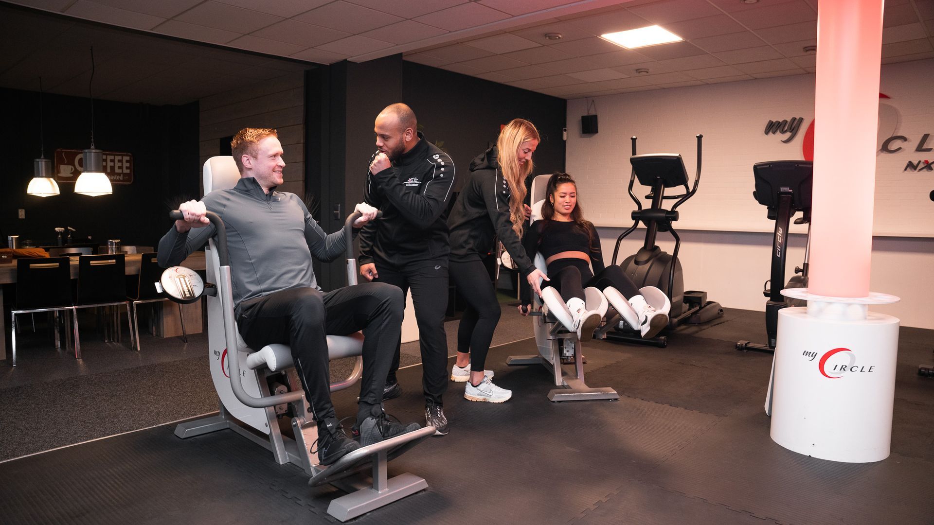 Mensen sporten in een sportschool onder begeleiding van instructeurs. Een man gebruikt een apparaat