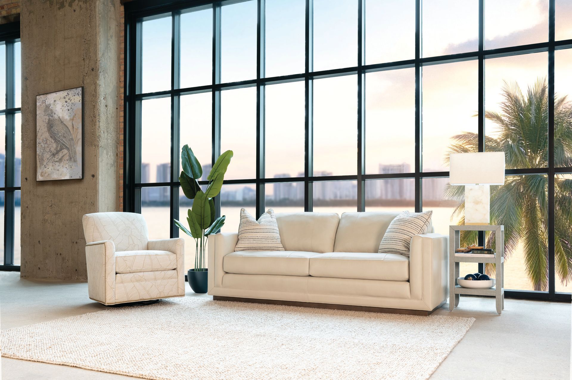 Living room with white sofa, armchair, side table, rug, and large windows with a scenic view.