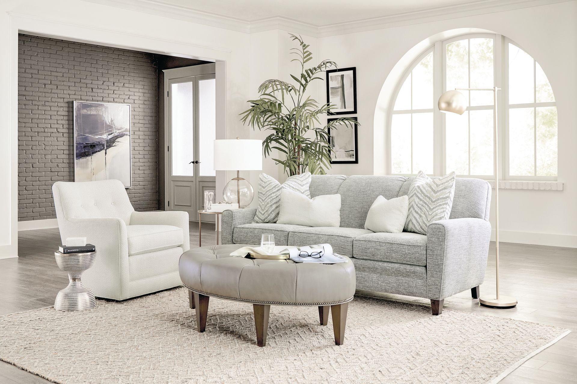 Living room with patterned sofa, white chair, and oval ottoman on a rug.