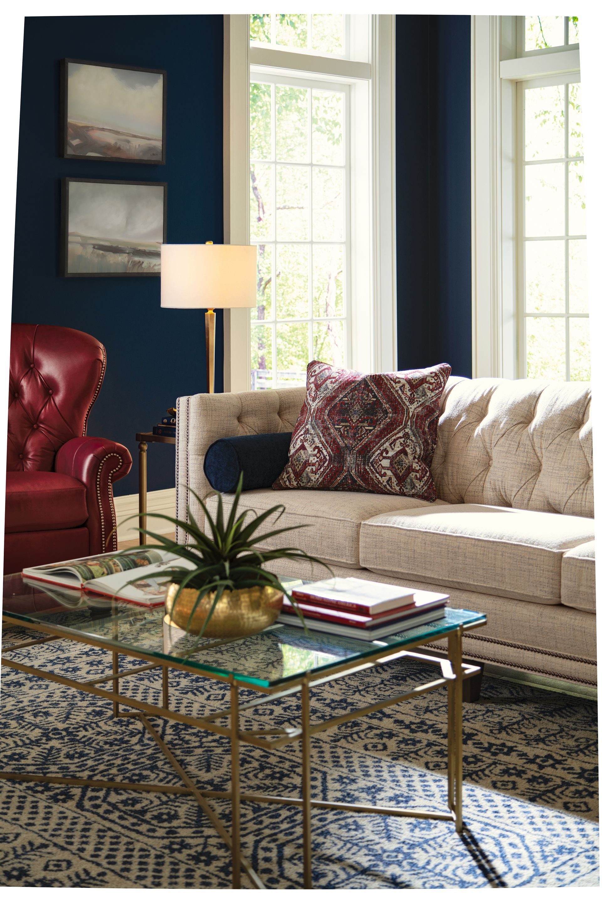 Living room with a tufted sofa, red chair, and gold accents.