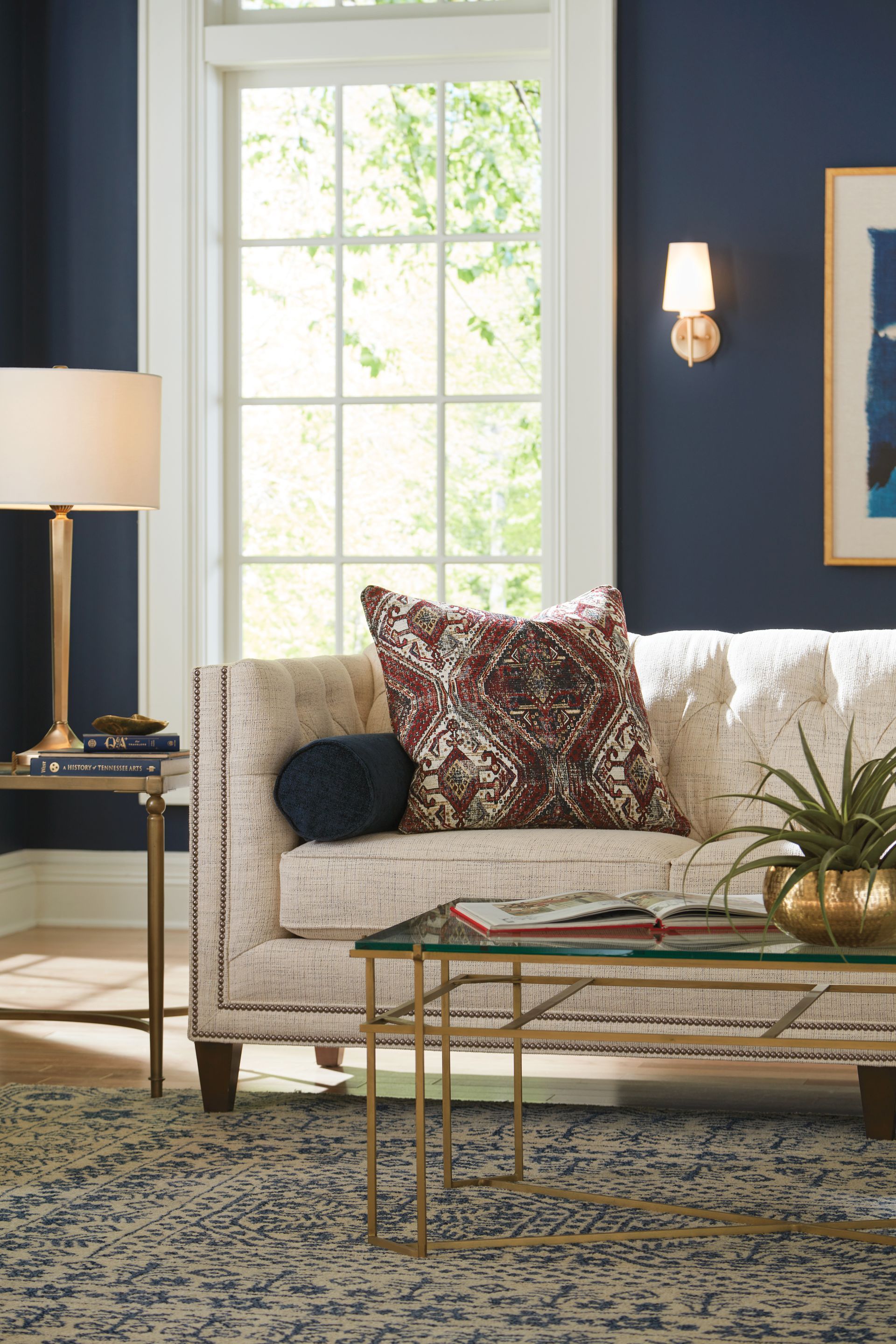 Living room with navy walls, cream sofa, and gold accents.
