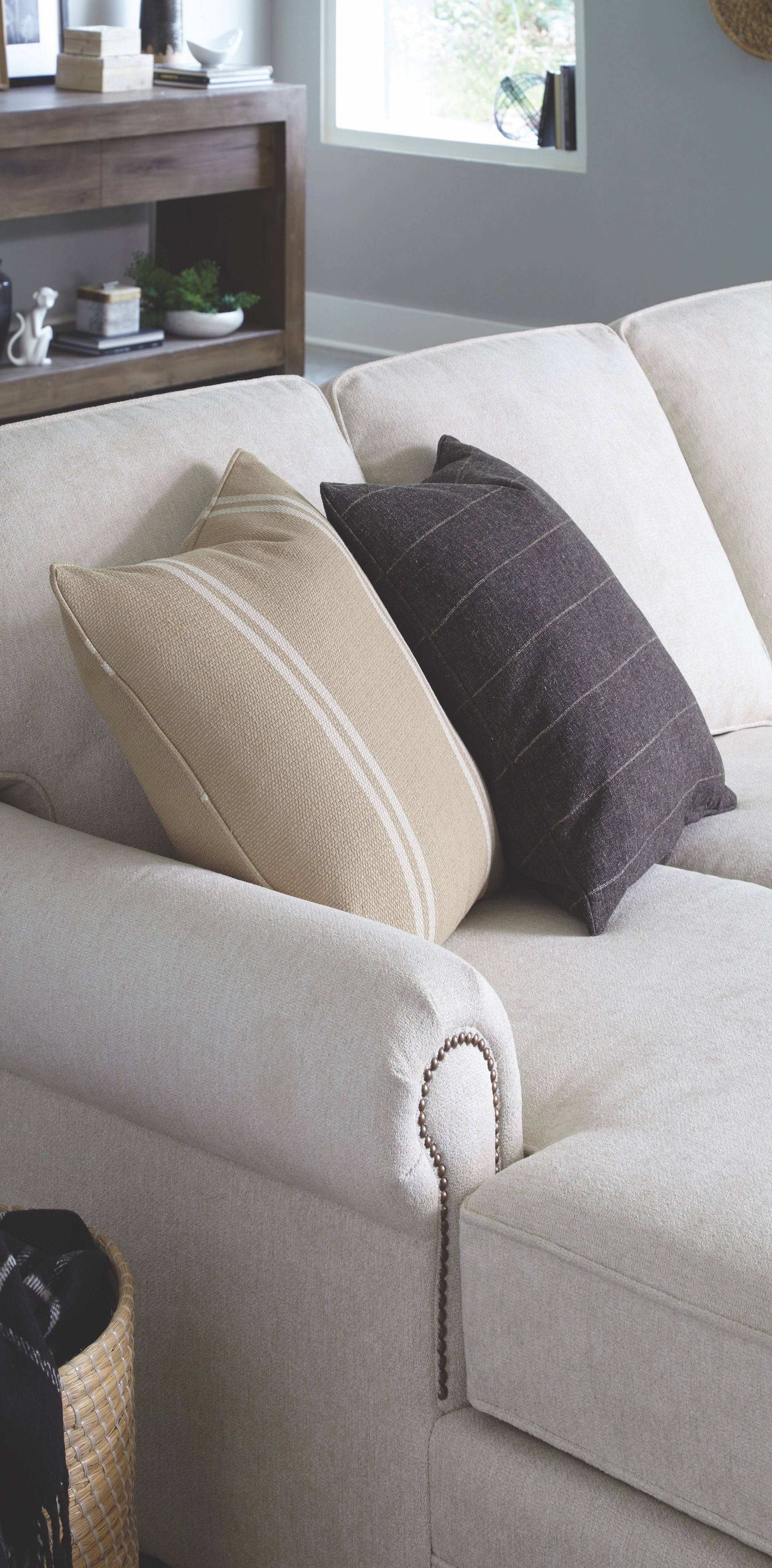 Off-white sectional sofa with throw pillows; a wooden console table is in the background.