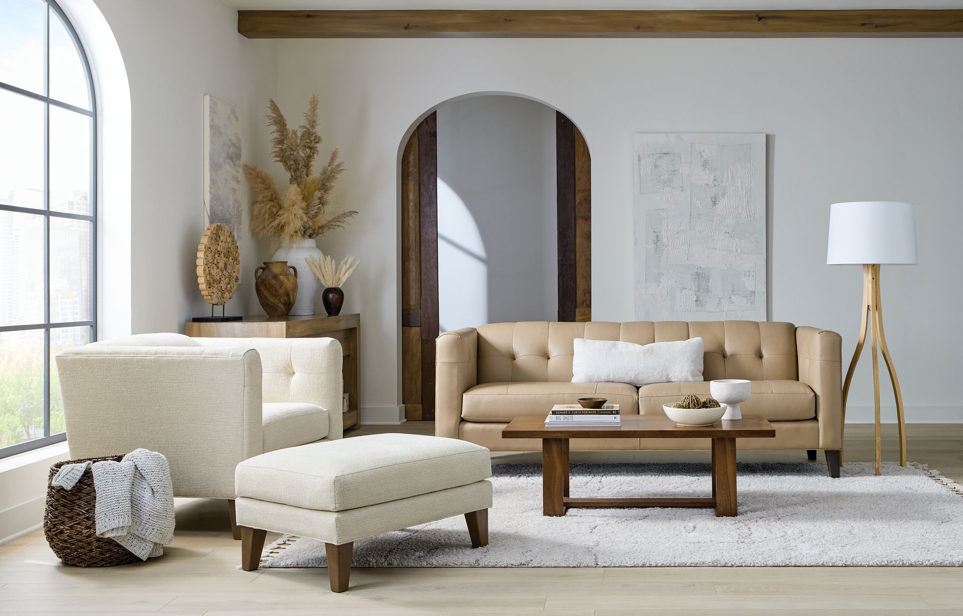 Living room with beige sofa, armchair, ottoman, coffee table, rug, and decorative items.