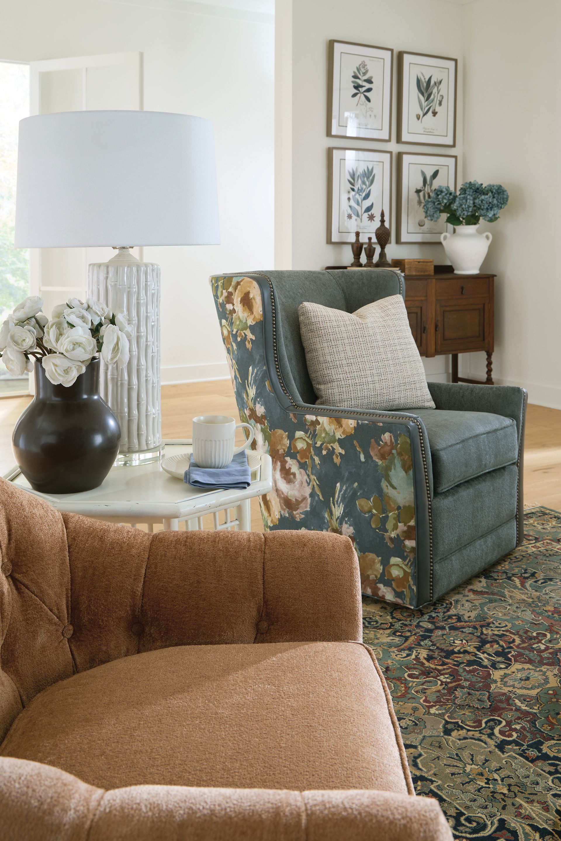 Cozy living room with floral armchair, brown sofa, and side table with lamp.