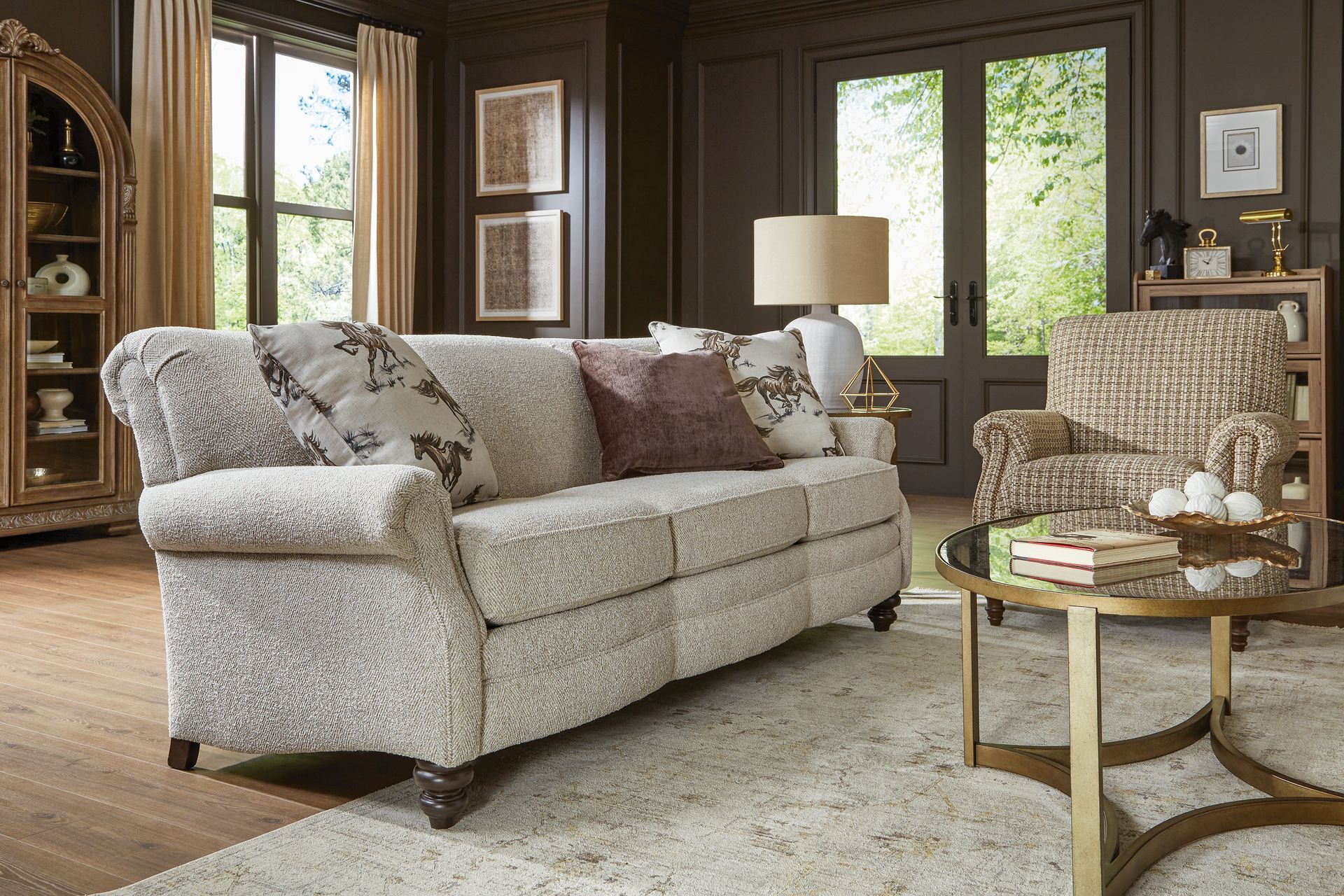 Living room with beige sofa, patterned armchair, round coffee table, and dark walls.