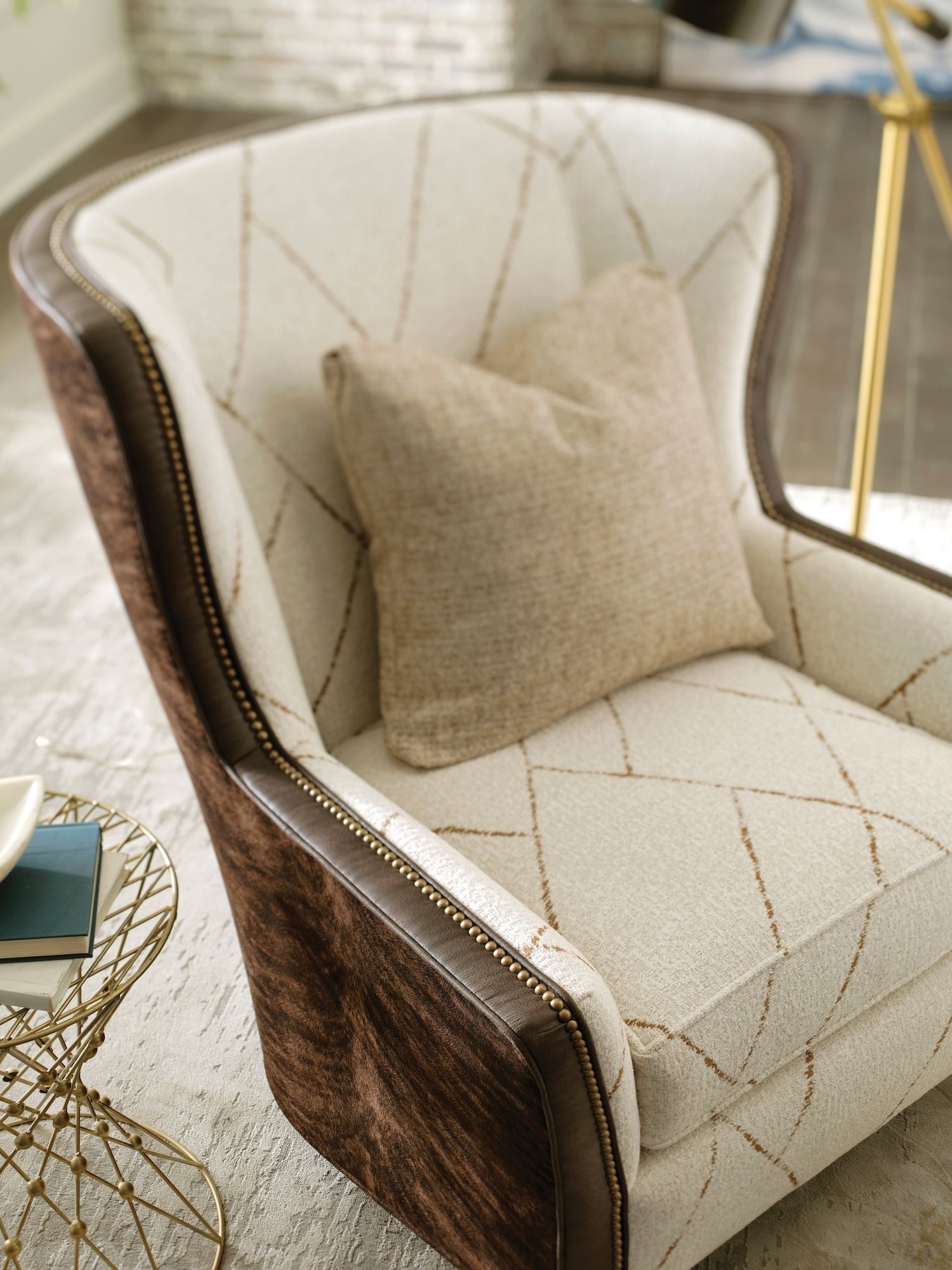 Tan and brown upholstered armchair with stitched pattern, a pillow, and a small side table.