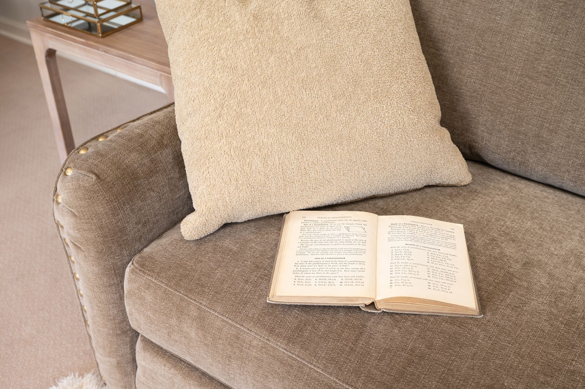 Open book with musical notes on a textured beige sofa with pillows, side table visible.