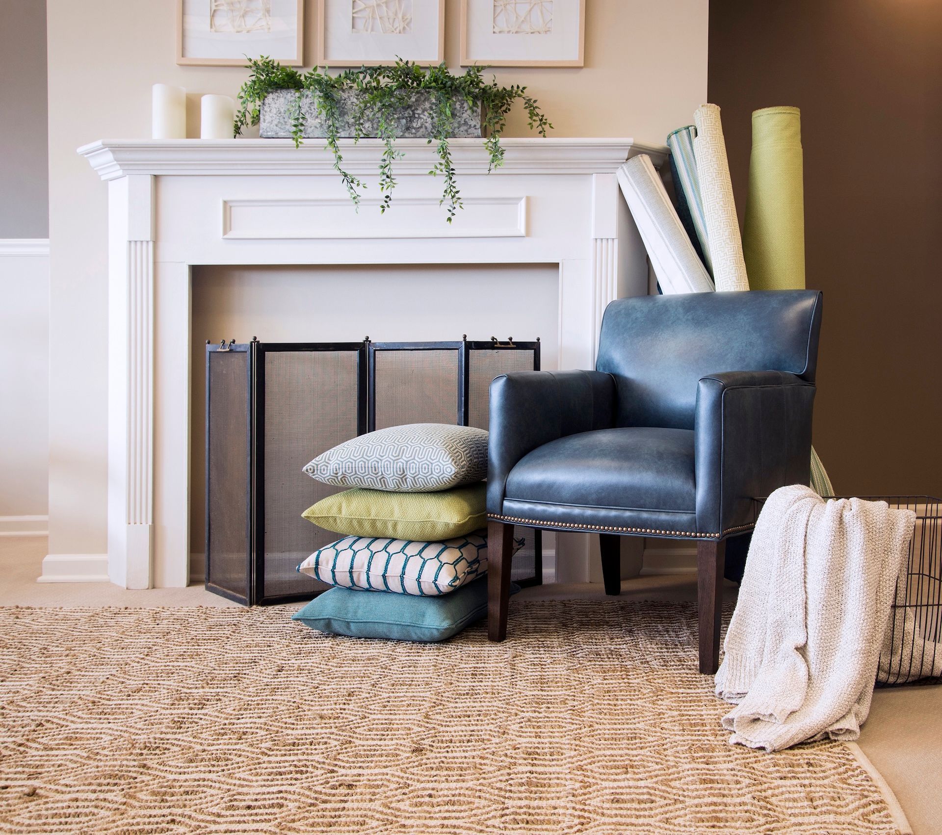 Living room with fireplace, blue chair, and stacked pillows on rug.
