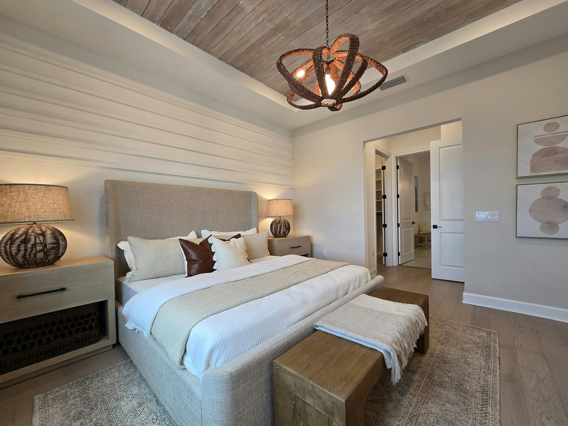 Bedroom with neutral tones, textured ceiling, upholstered bed, and artwork.