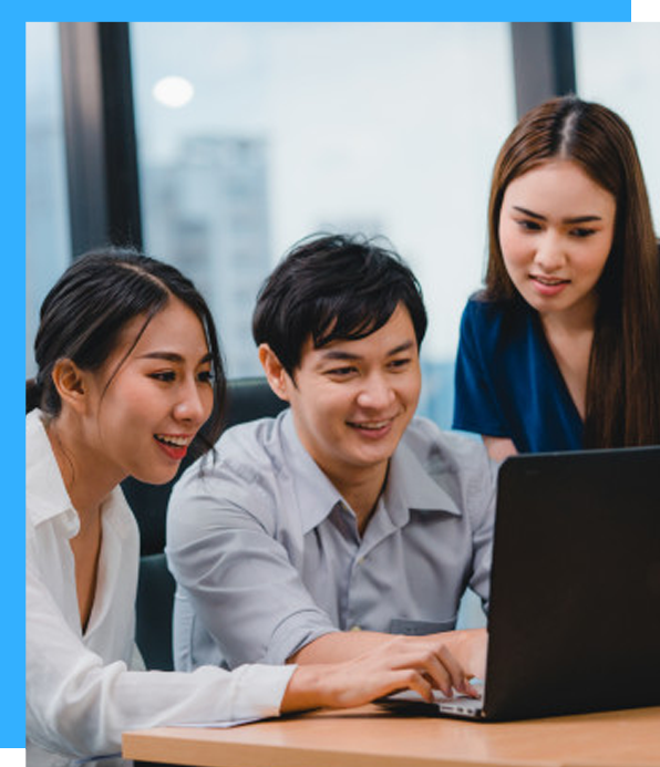 Three people looking at a laptop, smiling. Office setting.