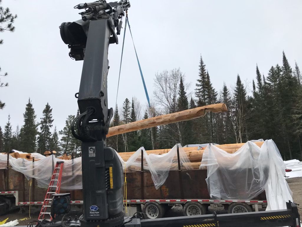 A large piece of wood is being lifted by a crane.